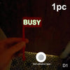 A hand holds up a red sign with the word BUSY, indicating a desk sign set for focused work.