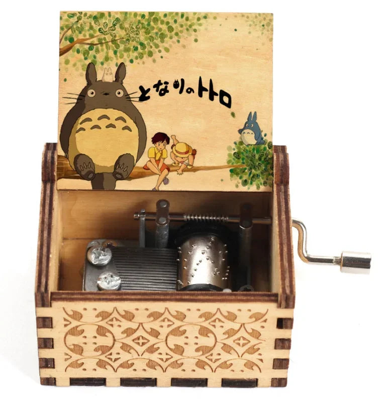 A hand-cranked wooden music box featuring a Totoro design on the lid.