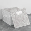 A rectangular sheet of faux marble 3D self-adhesive wall tiles displayed on a gray floor.