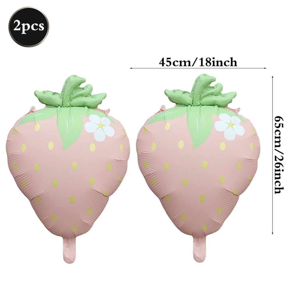 Two pink strawberry foil balloons with green leaves and white flowers