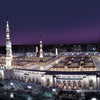 A panoramic view of the Masjid an Nabawi, featuring minarets and architecture, illuminated at night.
