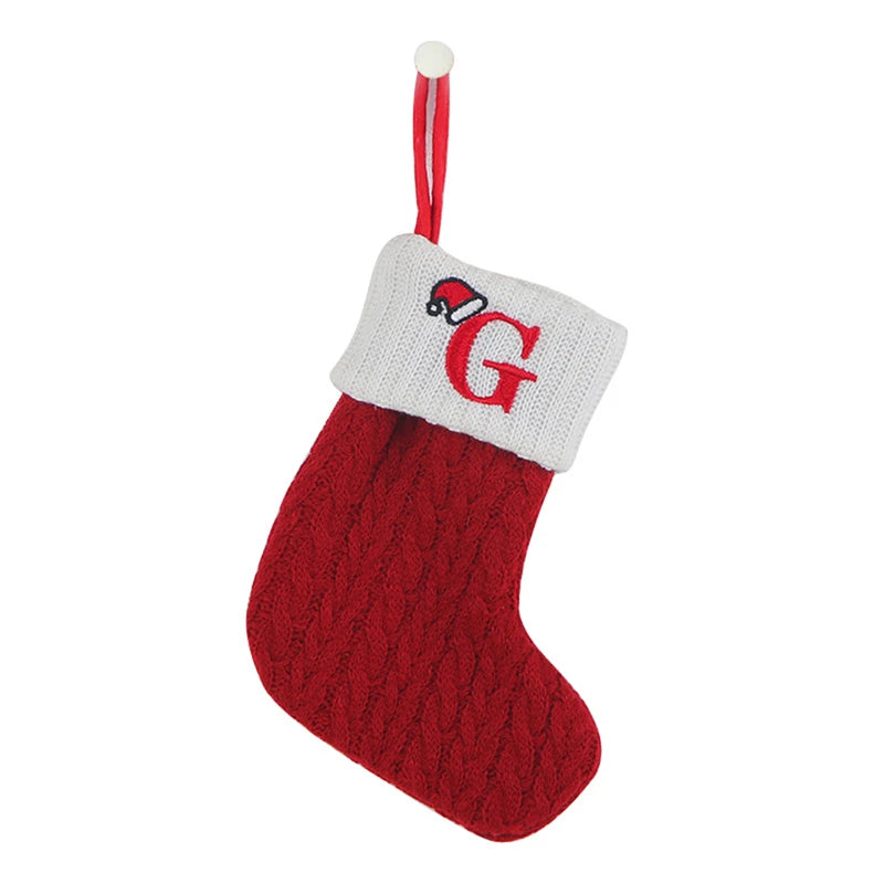 A red knitted sock with a white cuff featuring a red letter G and a hanging loop.