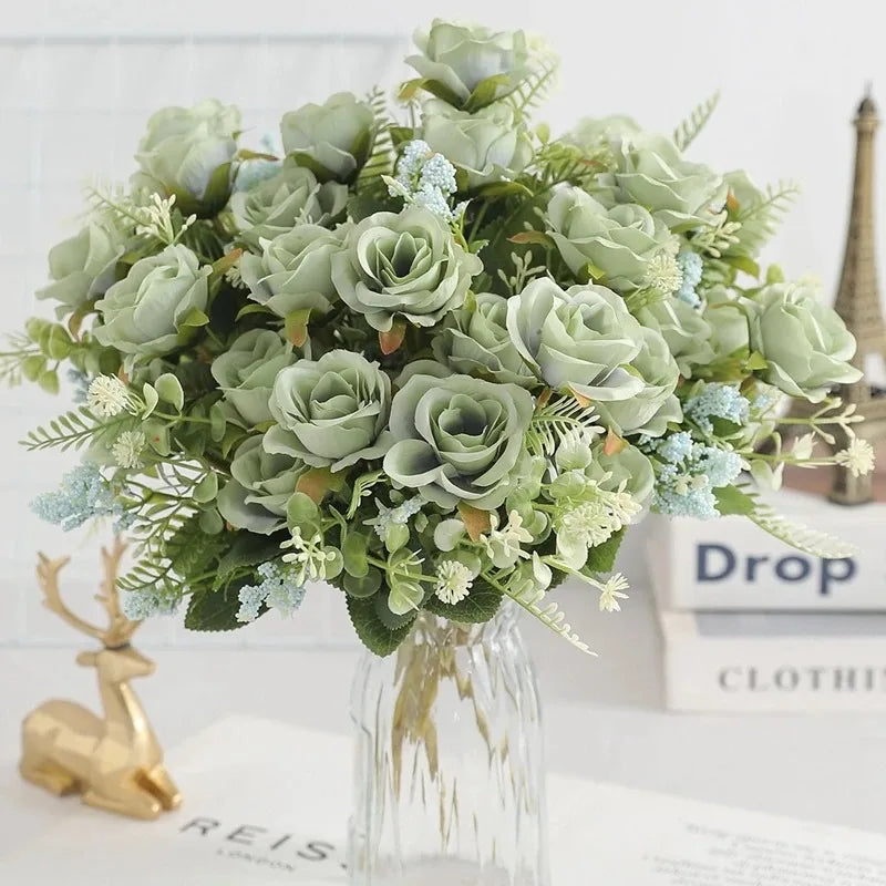 A bouquet of light green silk touch artificial roses with silvery-green foliage displayed in a glass vase.