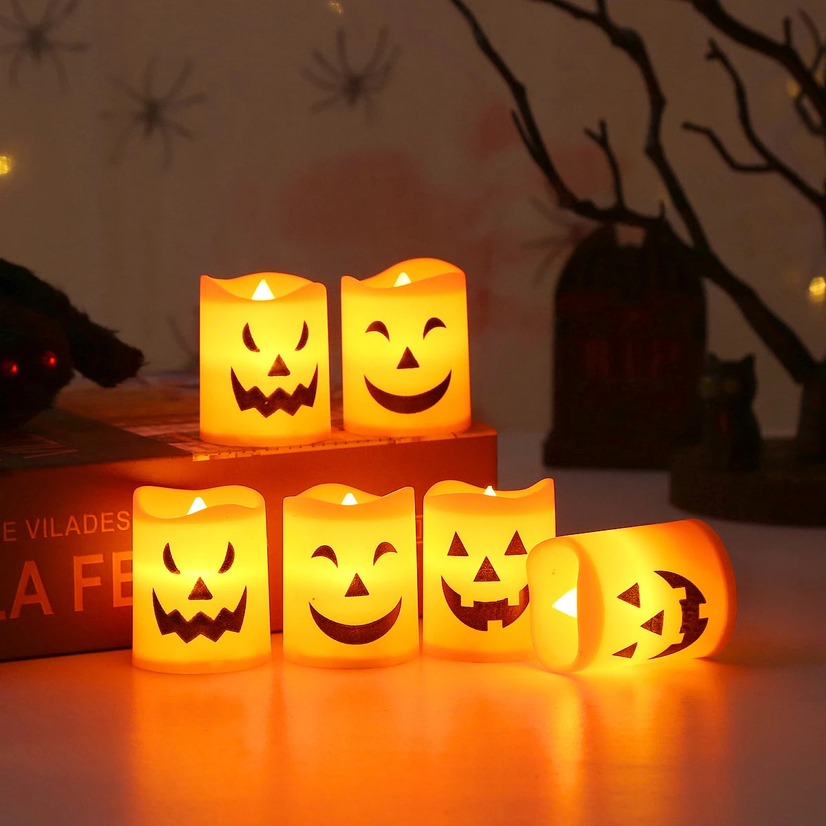 A set of six battery-powered LED Halloween candles with smiling and spooky faces casting an orange glow.