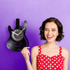 A woman holds a vintage vinyl record guitar wall clock against a purple background.