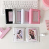 A collection of pink and silver compact photo card holders and an acrylic photo album are displayed on a white surface.