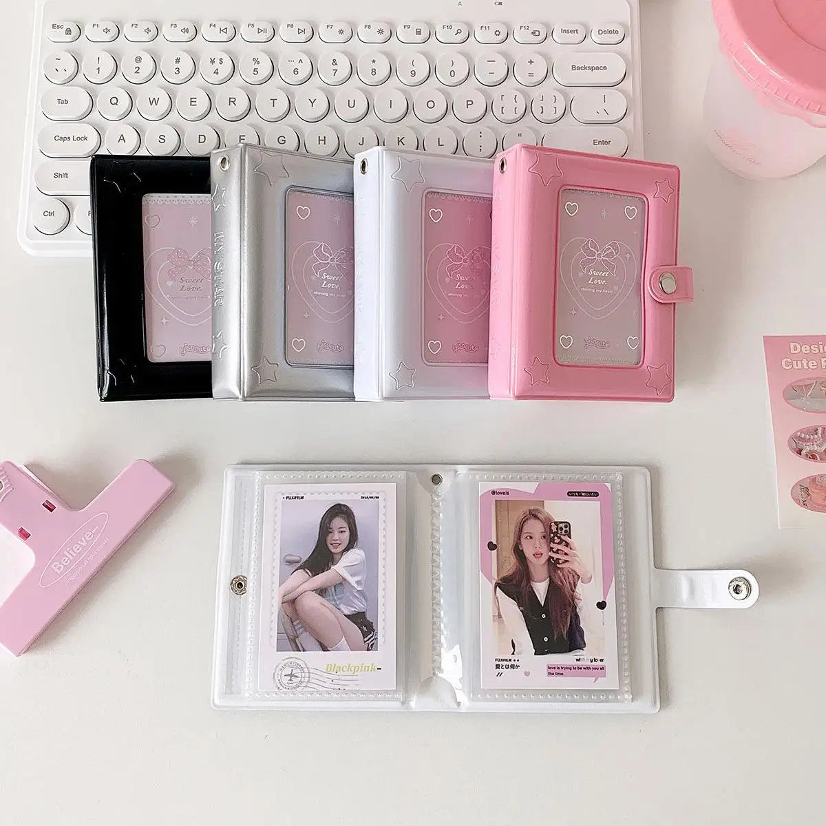 A collection of pink and silver compact photo card holders and an acrylic photo album are displayed on a white surface.