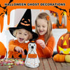 A young girl and boy smiling while holding a white ghost figurine in front of Halloween decorations.