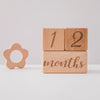 A stack of wooden baby milestone cards showing the numbers 1 and 2 and the word months
