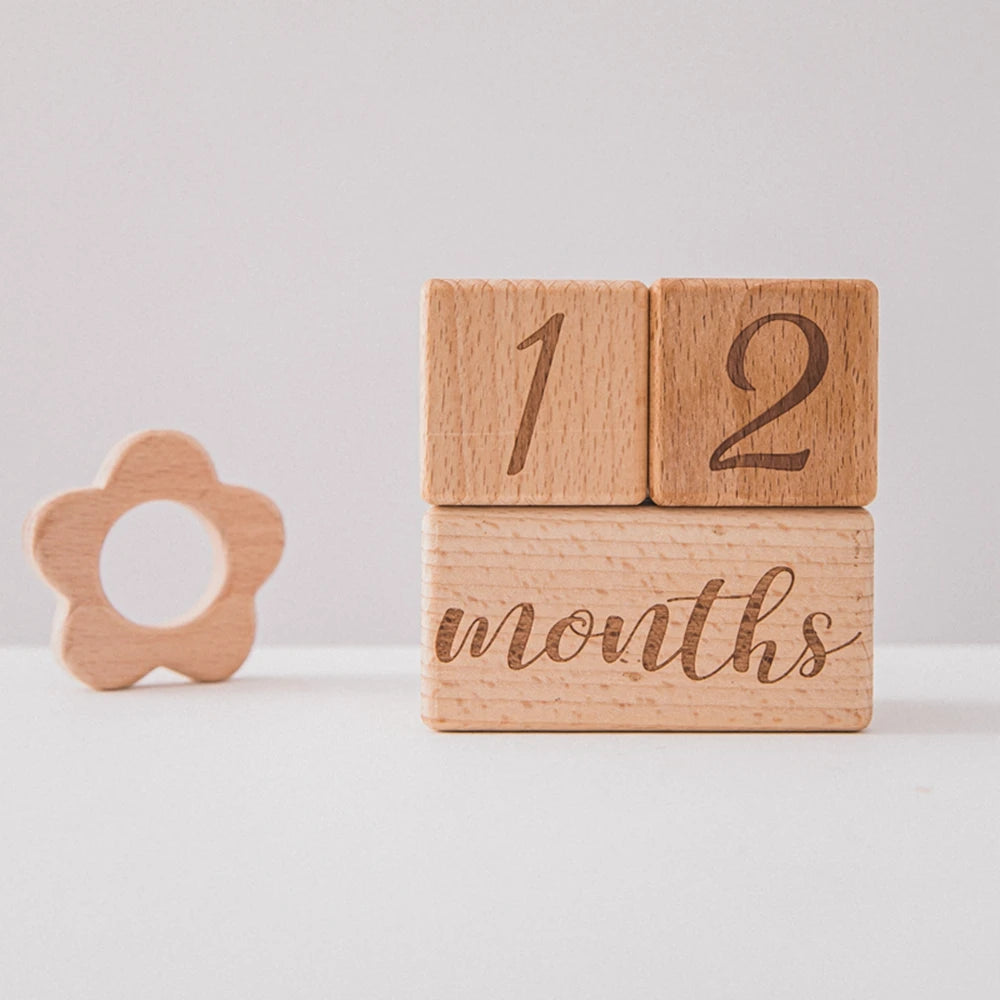 A stack of wooden baby milestone cards showing the numbers 1 and 2 and the word months