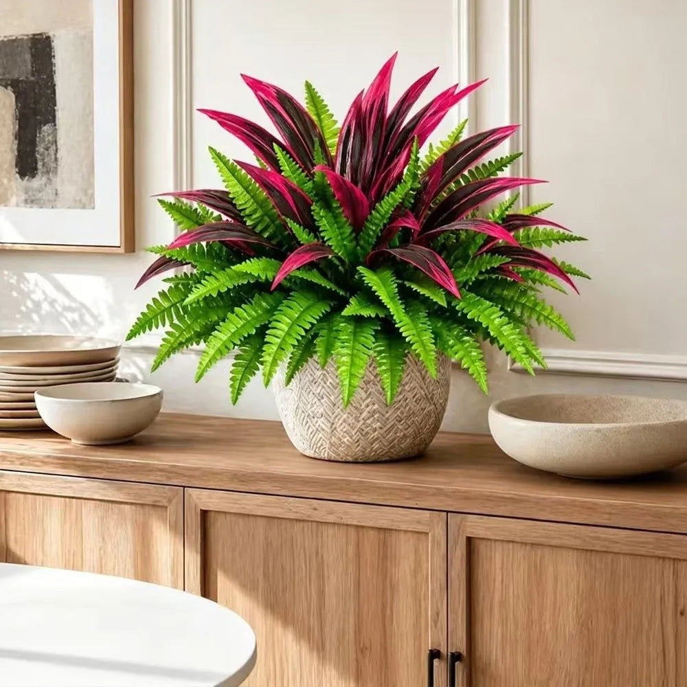 A potted artificial Dracaena Boston Fern with vibrant pink and green leaves sits on a wooden cabinet top.