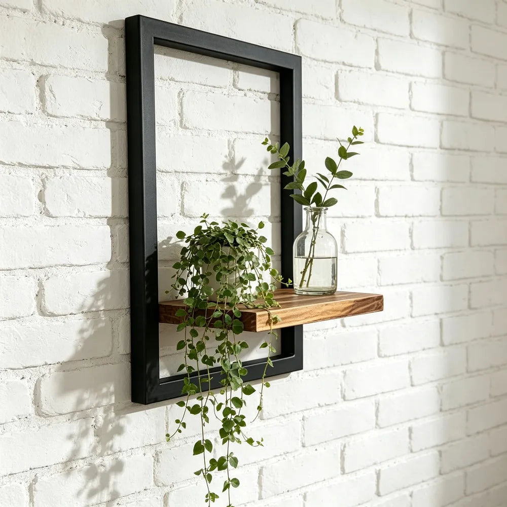 A black wooden floating wall shelf displaying a glass vase with greenery on a white brick wall.