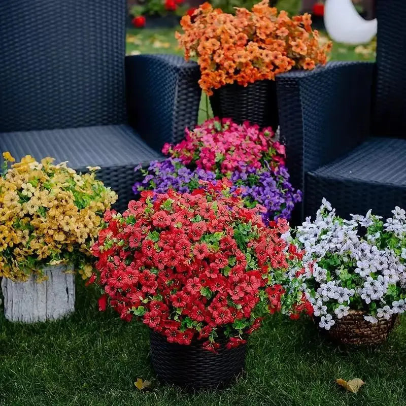 A vibrant bouquet of silk eucalyptus and violet artificial flowers planted in a black basket on green grass.