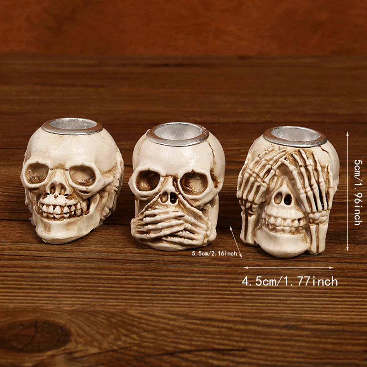 Three resin skull candle holders in off-white color displayed on a wooden surface.