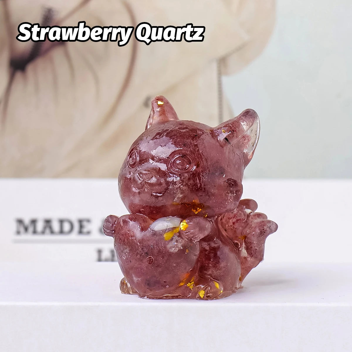 A small, translucent pink strawberry quartz crystal sculpture shaped like a fox for Feng Shui decor.