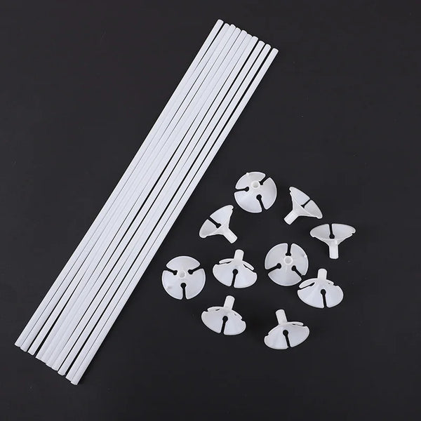 White macaron balloon sticks with holder cups arranged diagonally on a dark background