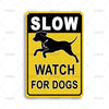 A yellow and black vintage metal tin sign with the text SLOW WATCH FOR DOGS and a silhouette of a dog running.