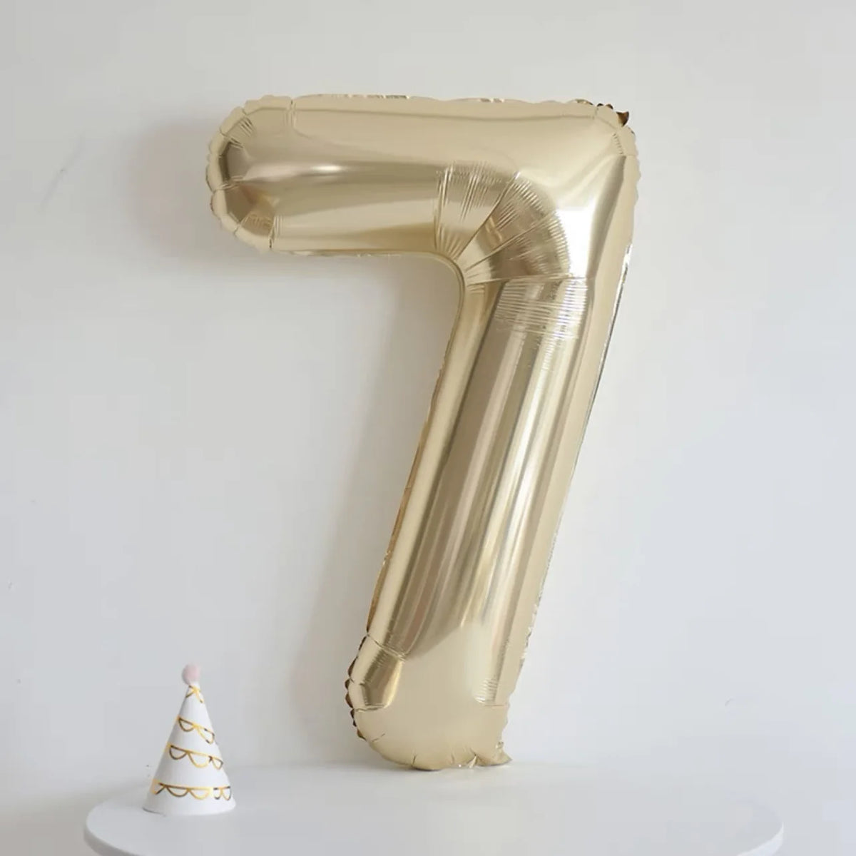 A large champagne gold foil number balloon shaped like the number 7 displayed against a white background.