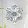 Silver resin flower wall art with layered petals mounted on a white wall.