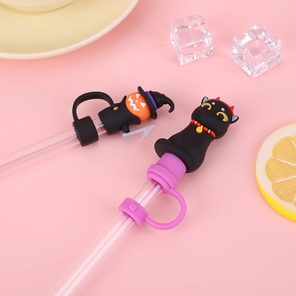 A silicone straw cover shaped like a black cat with orange eyes and purple accents, next to ice cubes.