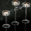 Three clear crystal glass candle holders with lit candles displayed on a black marble surface.