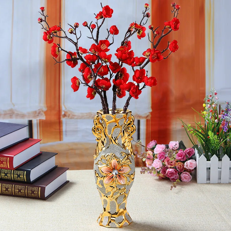 Gold-plated ceramic vase holding vibrant red blossoms against a soft background.