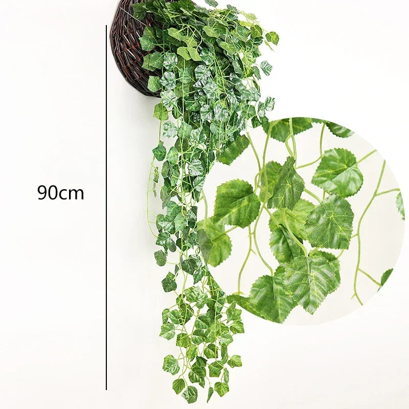Une longue cascade de plantes d'ivy vertes artificielles suspendues dans un panier en rotin foncé sur fond blanc.