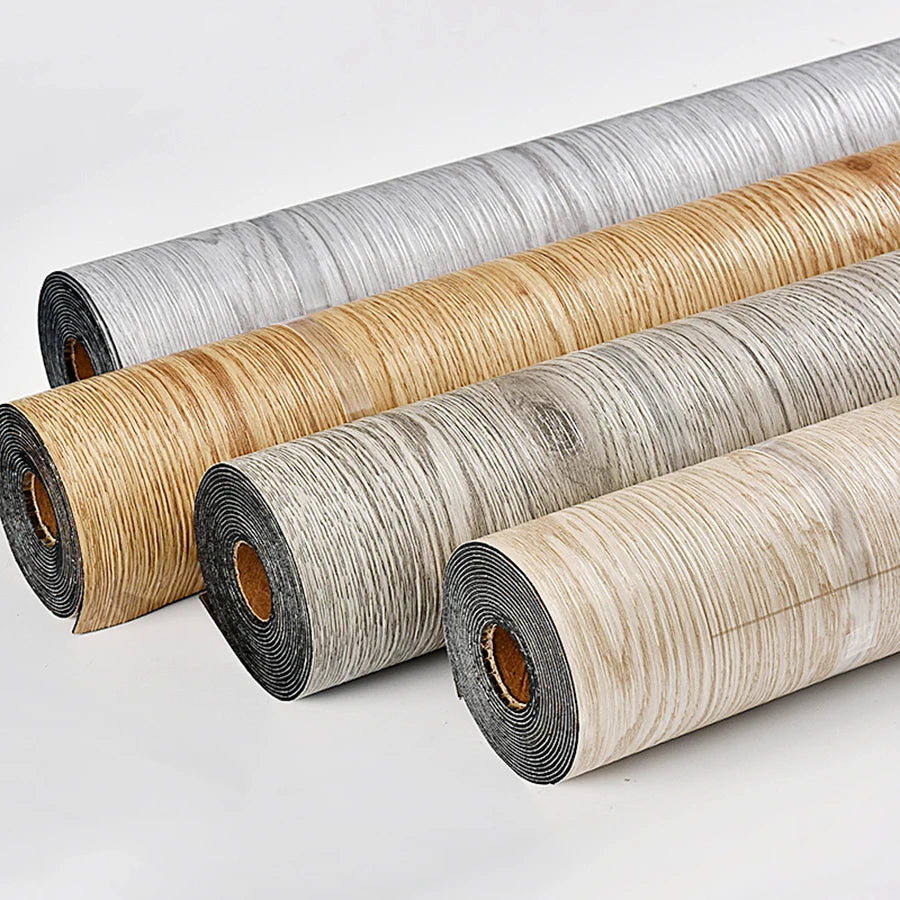Rolls of 3D textured wood grain self-adhesive flooring film in various natural wood tones