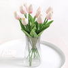 A bouquet of pink and white artificial tulip flowers in a clear glass vase