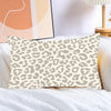A square decorative pillow cover with a beige and brown leopard print pattern resting on white bedding.