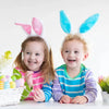 Two young children wearing colorful bunny ear headbands smiling for a photo.