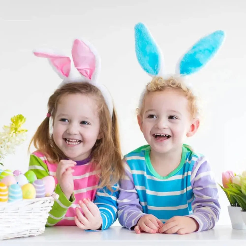Two young children wearing colorful bunny ear headbands smiling for a photo.