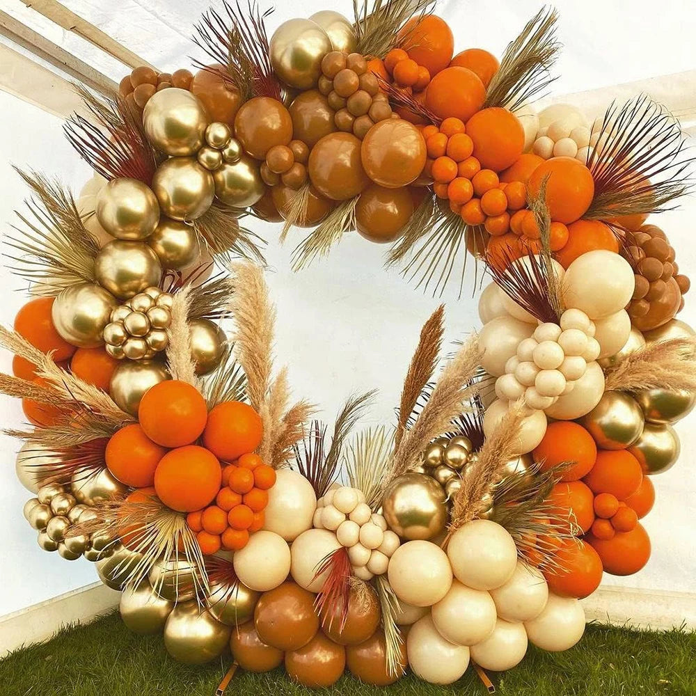 A floral wreath made of orange and gold latex balloons and dried grasses for party decor