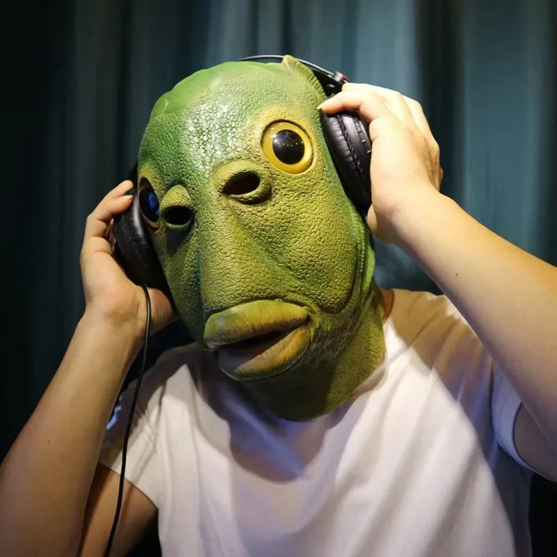A person is holding a realistic green animal mask with large eyes and ears, wearing headphones.