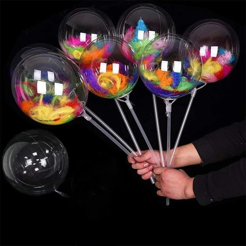 Several transparent balloons filled with colorful tissue paper are held by a person against a black background.