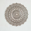 Decoración de pared tipo mandala de madera clara con intrincados patrones recortados montada en una pared blanca.