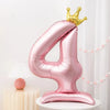 A pink foil number balloon shaped like the number 4 standing on a white pedestal.