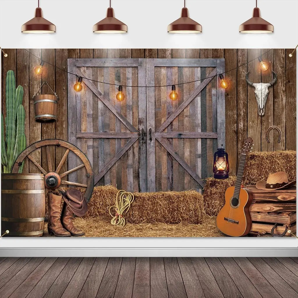 A rustic western backdrop featuring a wooden barn door, hay, antique tools, and guitar with hanging lights.