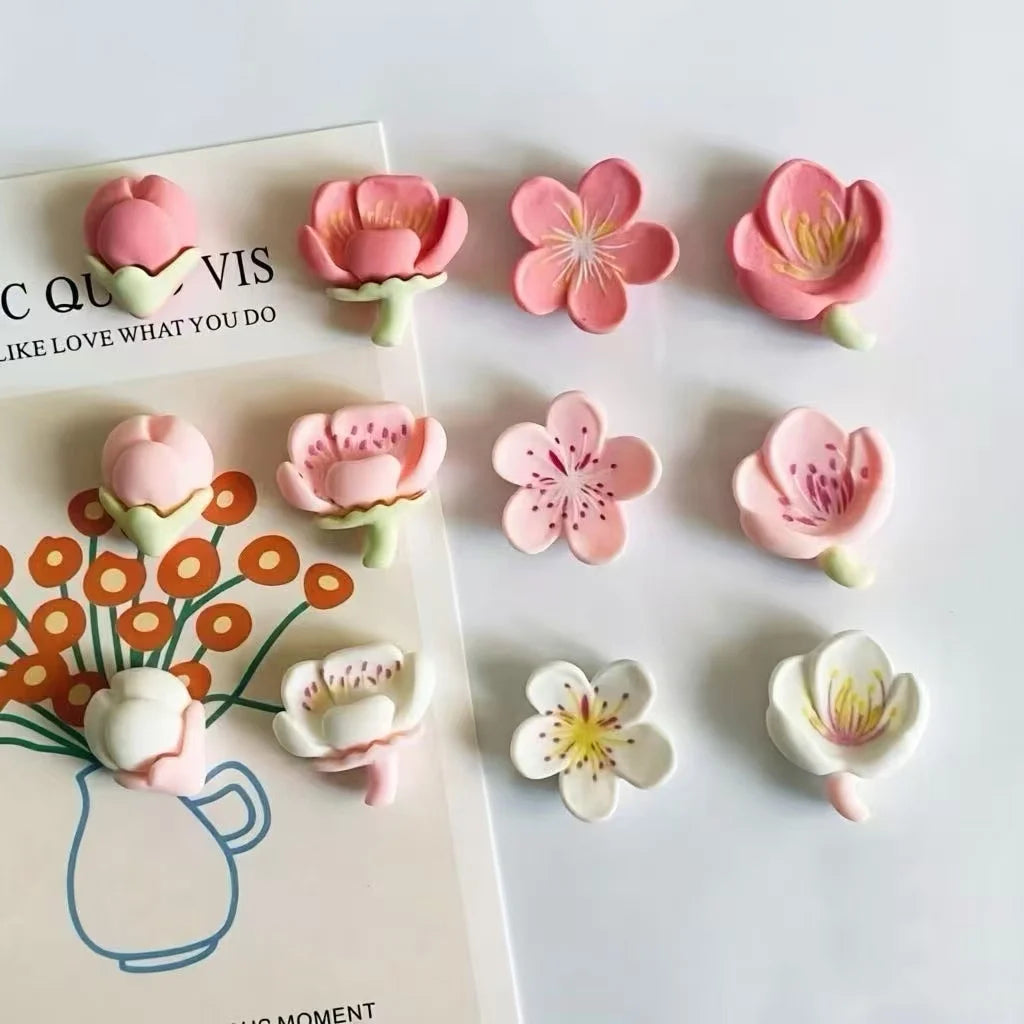 A set of 12 pink and white kawaii flower decorative fridge magnets arranged on a white background.