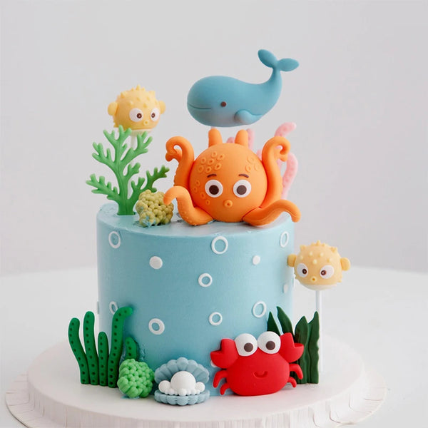 A cake decorated with ocean animal toppers including a blue whale, orange octopus, and pink turtle.