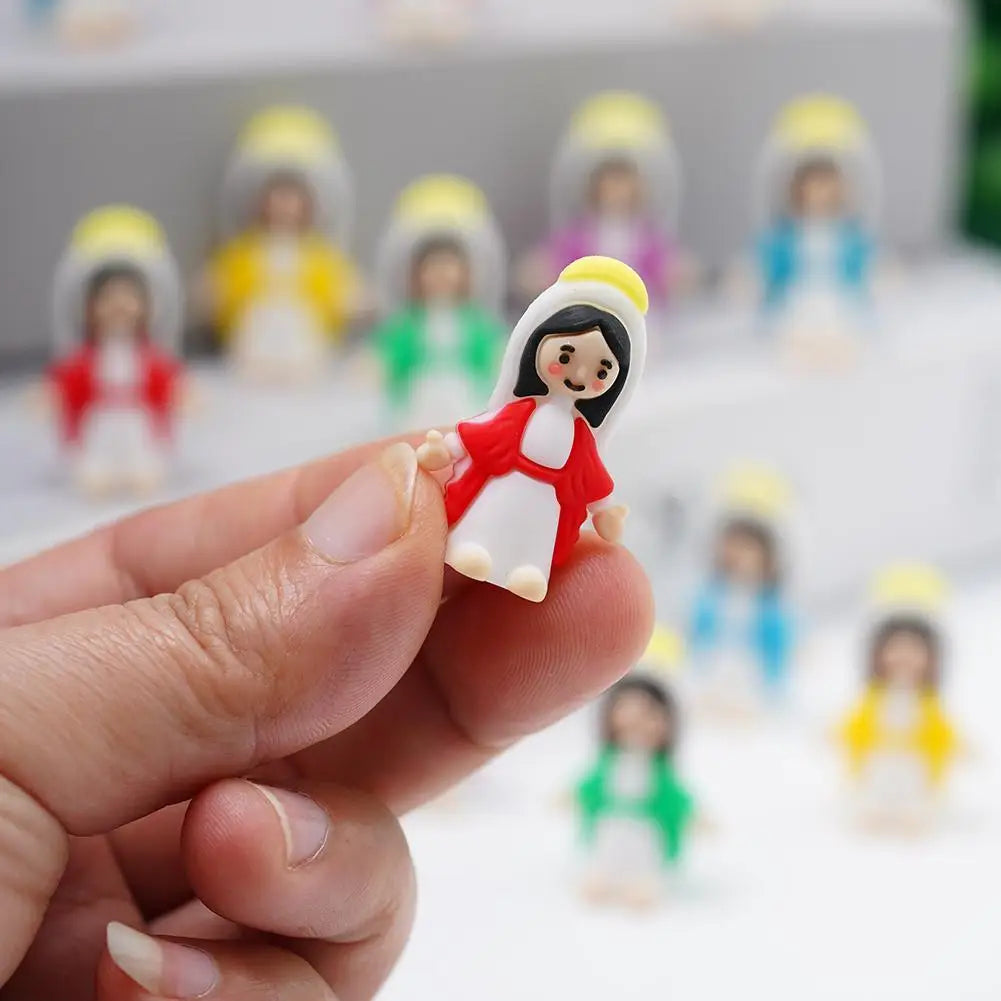 A hand holds a mini Maria religious desktop figurine ornament with a white and red dress against a blurred background of simi