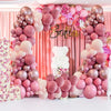 A backdrop decorated with pink and mauve latex balloons forming a floral arch for a celebration.