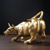 A golden sculpture of a ram in motion on a dark wooden surface.