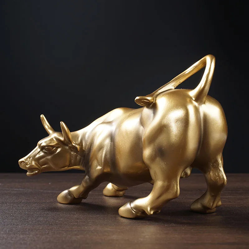 A golden sculpture of a ram in motion on a dark wooden surface.