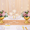 A table setting featuring rose ball centerpieces with silk artificial flowers and gold accents.