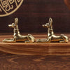 A pair of vintage brass pharaoh hound statues in an Egyptian-inspired style resting on a wooden surface.