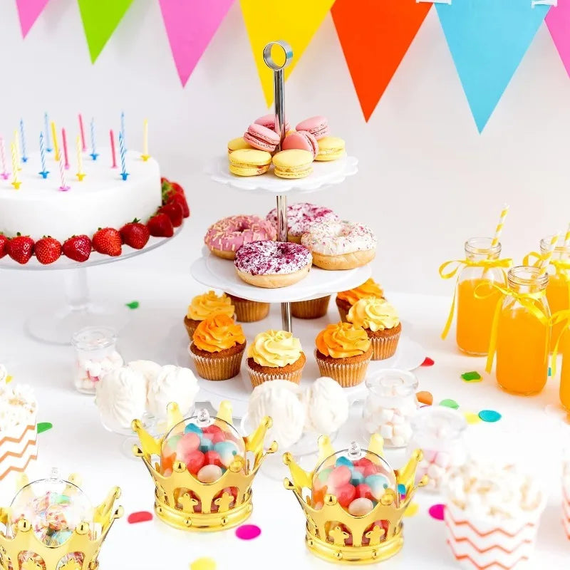 A display of gold crown-shaped candy boxes and various colorful sweets on a white surface.