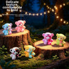 A set of colorful resin bear figurines in various shades and textures displayed on wooden stumps in a natural outdoor setting
