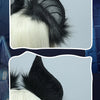 A close-up of a black bat simulation headpiece with white hair, shown against a blue background.