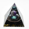 Handmade resin orgonite pyramid with natural obsidian and copper coil set against a dark background